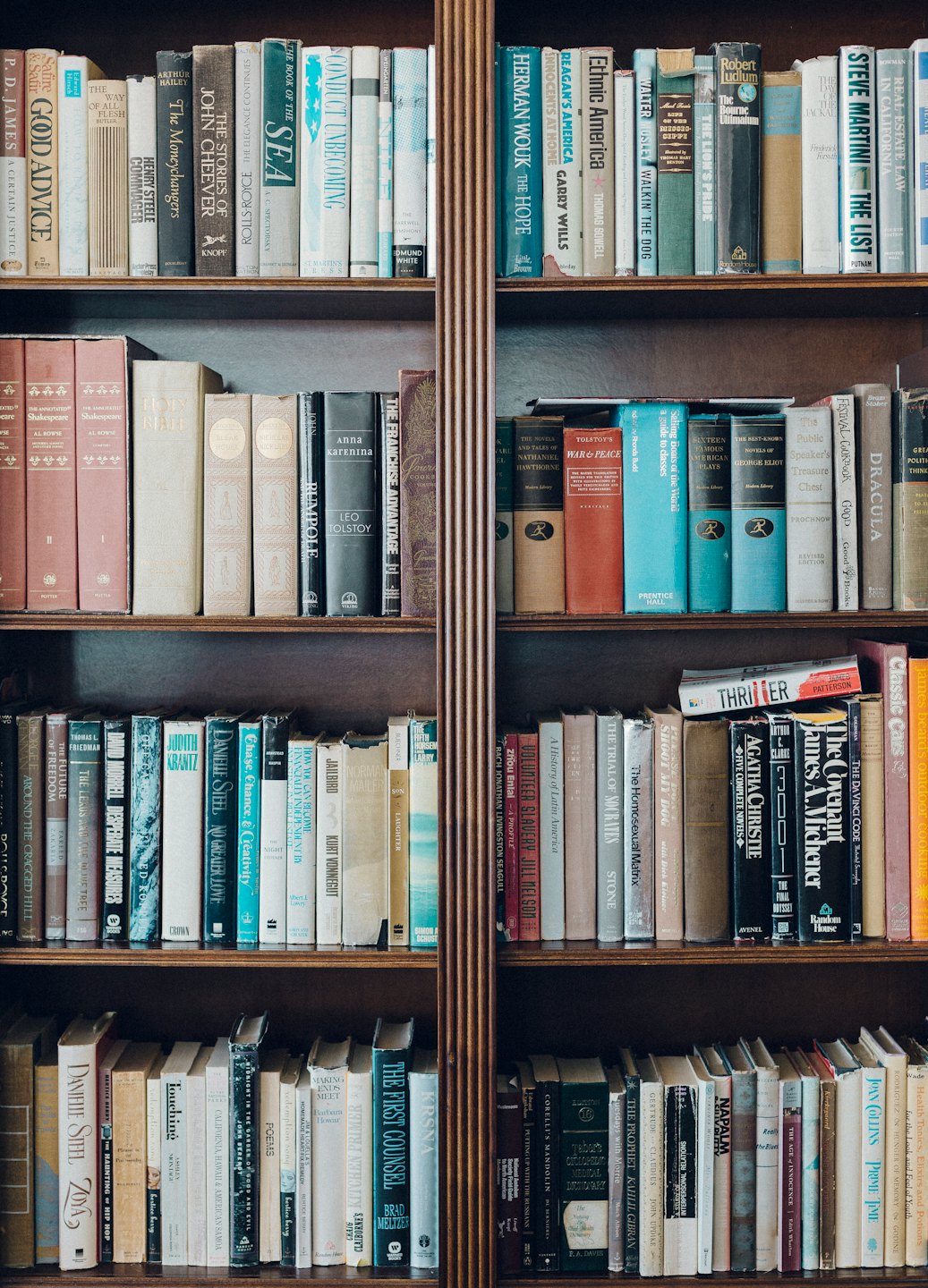 A tall wooden bookshelf filled with many old and colorful books.