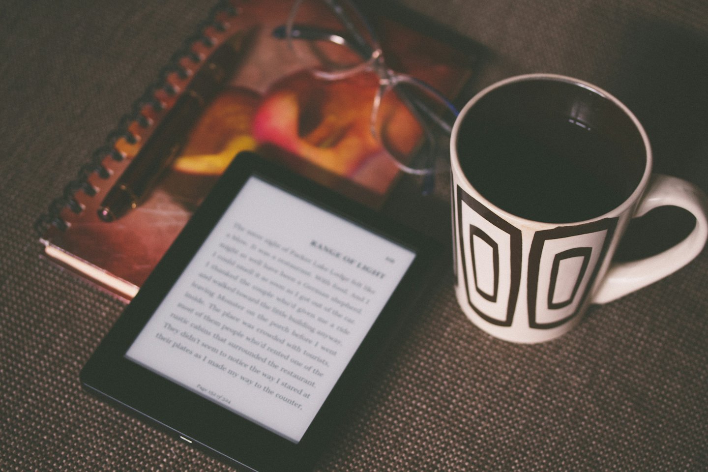 Black e-reader displaying a novel on a textured surface.